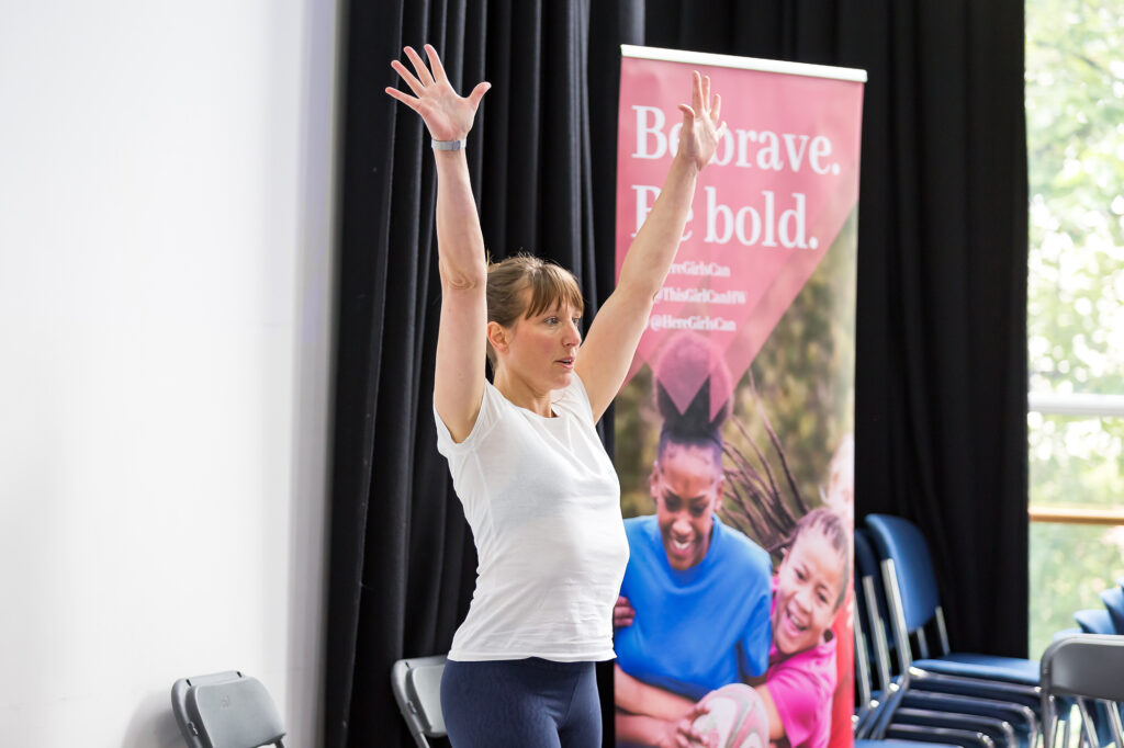 Jenny-May While teaching with arms raised, teaching at HGC Teacher Conference.